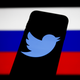 A phone with the Twitter logo on it in front of the Russian flag.